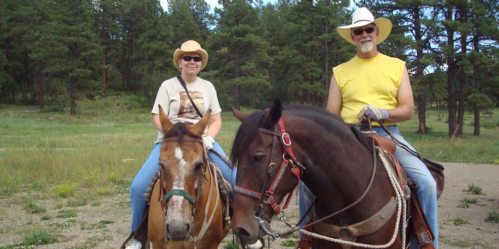couple with cowboy hats on horseback