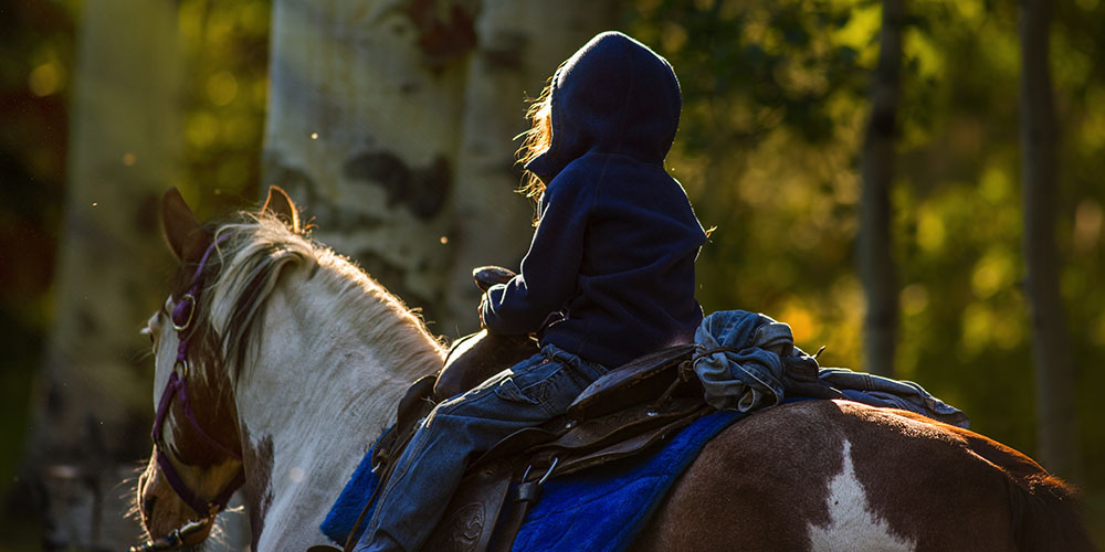 Kid in hoodie on a horse riding near Pagosa Springs