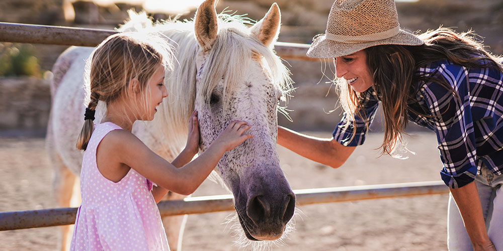 Mom and daughter petting a white horse